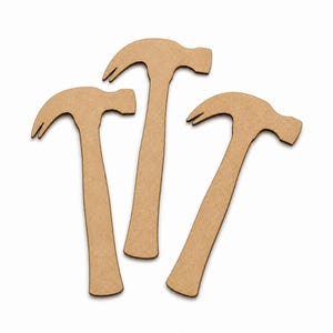 May include: Three flat, tan-coloured hammer-shaped cutouts made of a smooth, compressed wood material. Each cutout features the distinct silhouette of a claw hammer with a curved handle and a head with a claw and striking face, arranged in a cluster.