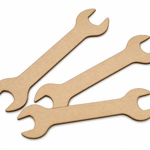 May include: Three flat, light brown, wrench-shaped cutouts made of a smooth, matte material. Each piece features an open-ended spanner design with a long, straight handle and a U-shaped head at both ends, arranged in a slightly overlapping pattern.