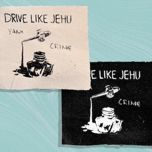 May include: Two fabric patches with the text "Drive Like Jehu" and "Yank Crime" printed on them. The patches are black and white and have a distressed look.