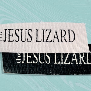 May include: Two fabric labels with the text "the JESUS LIZARD" printed on them. The top label is white with black text, and the bottom label is black with white text.