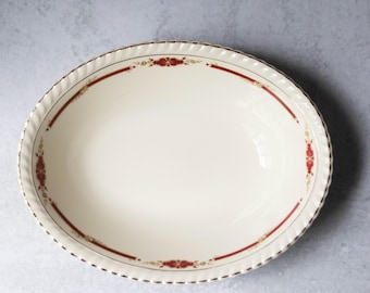 May include: A white oval serving bowl with a red and gold floral design around the rim.