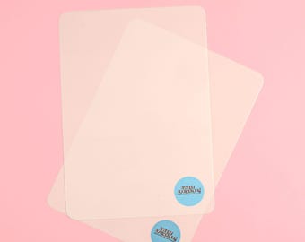 Puede incluir: Dos hojas de papel rectangulares, blancas y translúcidas, con una pegatina circular azul en cada una. La pegatina dice "Total Remarkable" en texto blanco.