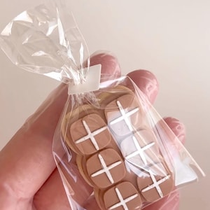 May include: A clear plastic bag filled with six brown and white cross-shaped cookies.