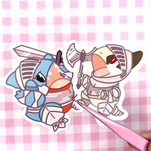 May include: Two stickers depicting cartoon characters in knight armour. One is blue with a sword, the other is yellow with an axe. The stickers have a white border and are on a pink and white checked background.