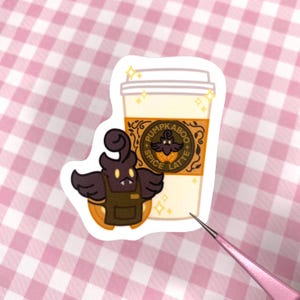 May include: A sticker featuring a cartoon character holding a cup of pumpkin spice latte. The cup has a logo that says "Pumpkinaboo Spice Latte".