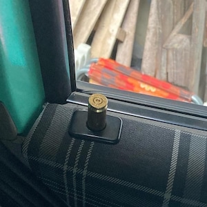 May include: A close-up of a car door with a plaid fabric interior. The door handle has a brass bullet-shaped knob.