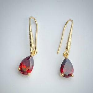 Peut inclure: Une paire de boucles d'oreilles pendantes en or avec des pierres précieuses rouges en forme de goutte.