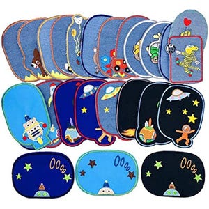 Może przedstawiać: Kolekcja dżinsowych naszywek z różnymi haftowanymi wzorami. Naszywki przedstawiają obrazy zwierząt, pojazdów, robotów i elementów kosmicznych, takich jak gwiazdy, planety i UFO. Niektóre naszywki mają wyhaftowaną liczbę "0000".