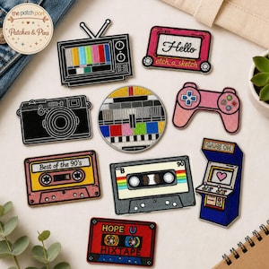 Puede incluir: Una colección de parches bordados con diseños retro que incluyen un televisor con barras de color, un juguete de dibujo rojo con el texto Hello etch_a_sketch, una cámara negra, un patrón de prueba circular, un mando de juego rosa y tres casetes.