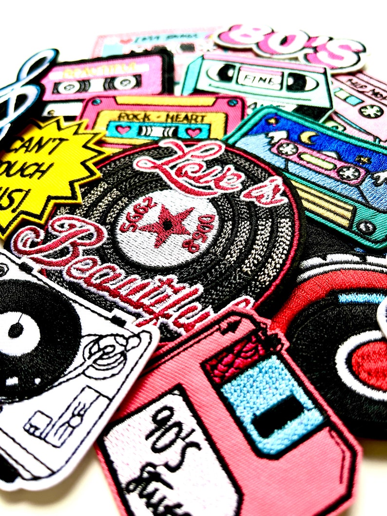 May include: A collection of colorful embroidered iron-on patches featuring music-themed designs, including cassette tapes, records, and the words "Love is Beautiful" and "80s Funk".