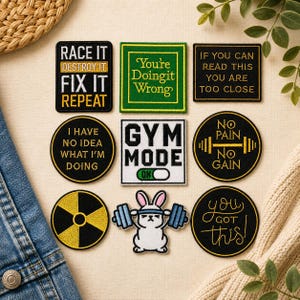 May include: A collection of nine embroidered patches featuring various designs and text, including phrases like Race It Destroy It Fix It Repeat, You're Doing It Wrong, If You Can Read This You Are Too Close, Gym Mode On, and a rabbit lifting a barbell.