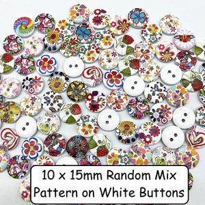 Puede incluir: Una colecci&oacute;n de botones de madera blanca de 10 mm por 15 mm con una variedad de coloridos patrones florales. El texto "10 x 15mm Random Mix Pattern on White Buttons" est&aacute; impreso debajo de los botones.