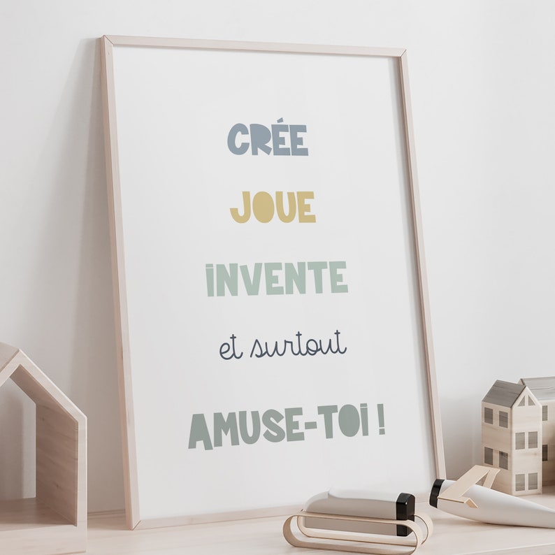 May include: A framed print with the text "Cr&eacute;e joue invente et surtout amuse-toi!" in a variety of colors, including blue, yellow, and green. The print is on a white background and is framed in a light wood frame.