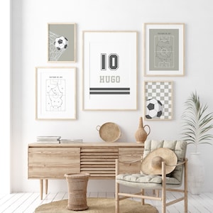 May include: A white wall with five framed prints, including a soccer jersey with the number 10 and the name Hugo, a soccer ball in a net, a soccer field with a game plan, and a soccer ball on a checkered background. A wooden chair with a straw hat on it sits in front of a wooden cabinet with a woven basket.