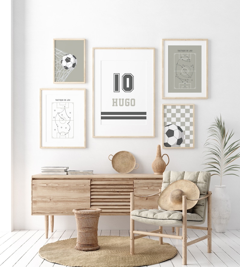 May include: A white wall with five framed prints, including a soccer jersey with the number 10 and the name Hugo, a soccer ball in a net, a soccer field with a game plan, and a soccer ball on a checkered background. A wooden chair with a straw hat on it sits in front of a wooden cabinet with a woven basket.