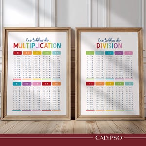 May include: Two framed educational wall charts with light wood frames. The left chart is titled Les tables de MULTIPLICATION and the right is titled Les tables de DIVISION. Both feature colorful headers and columns of math equations from 1 to 10.