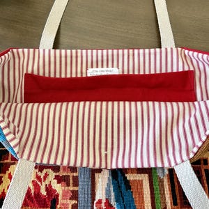 Op de afbeelding: Een draagtas met een rood-wit gestreepte binnenvoering, voorzien van een effen rood horizontaal vak en twee beige geweven stoffen hengsels. Een klein wit label is aan de binnenkant genaaid met de tekst Etsy.com/shop/PalmAndPinesDesign.