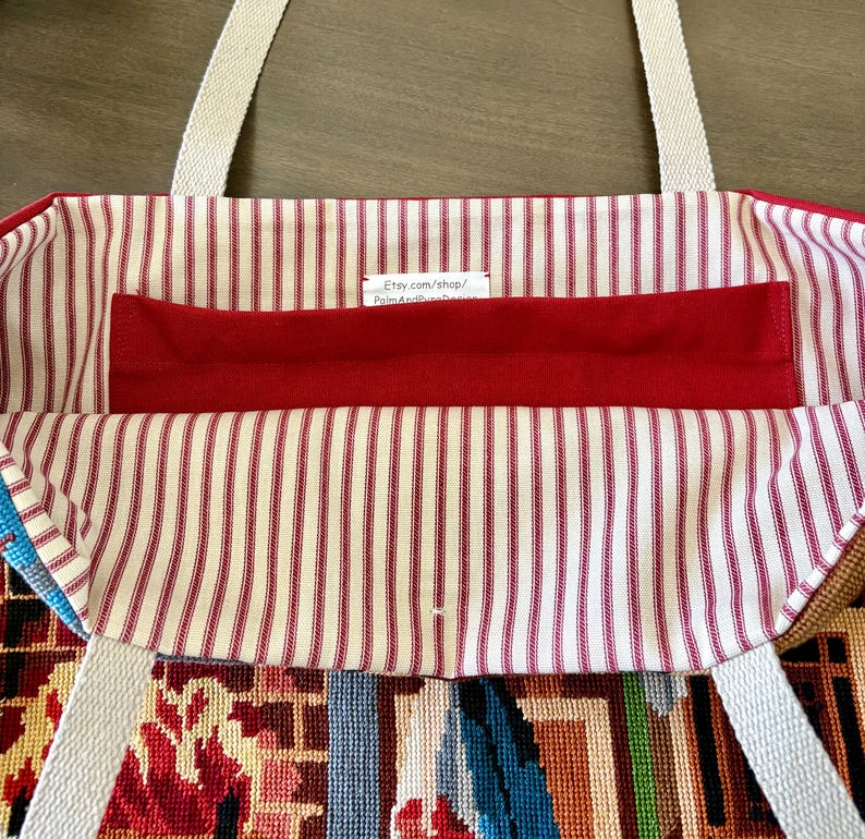 Op de afbeelding: Een draagtas met een rood-wit gestreepte binnenvoering, voorzien van een effen rood horizontaal vak en twee beige geweven stoffen hengsels. Een klein wit label is aan de binnenkant genaaid met de tekst Etsy.com/shop/PalmAndPinesDesign.