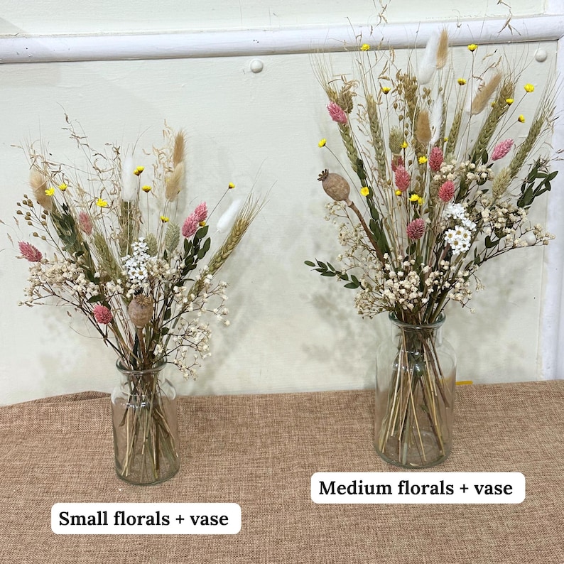 May include: Two glass vases filled with dried floral arrangements. The vase on the left is smaller and labeled "Small florals + vase". The vase on the right is larger and labeled "Medium florals + vase".