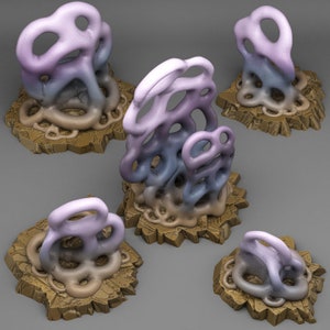 May include: Five abstract sculptures made of a purple, blue, and brown material. The sculptures are on a brown, rocky base.