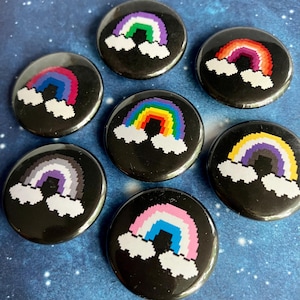 May include: Seven rainbow pride flag pins with pixelated rainbow designs and white clouds on a black background.