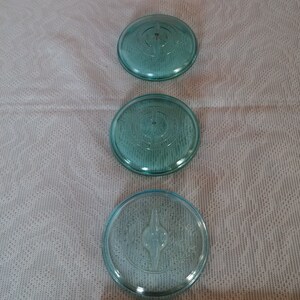 Vintage blue- green bail top canning jar lida. Group of three. One has small crack in center other two good. 3" wide. No chips.