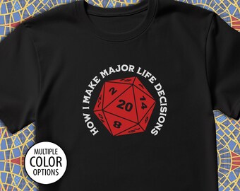 May include: Black t-shirt with a white circle around a red 20-sided die. The text "How I Make Major Life Decisions" is written around the die.