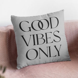 May include: A grey throw pillow with the text "GOOD VIBES ONLY" in black lettering.