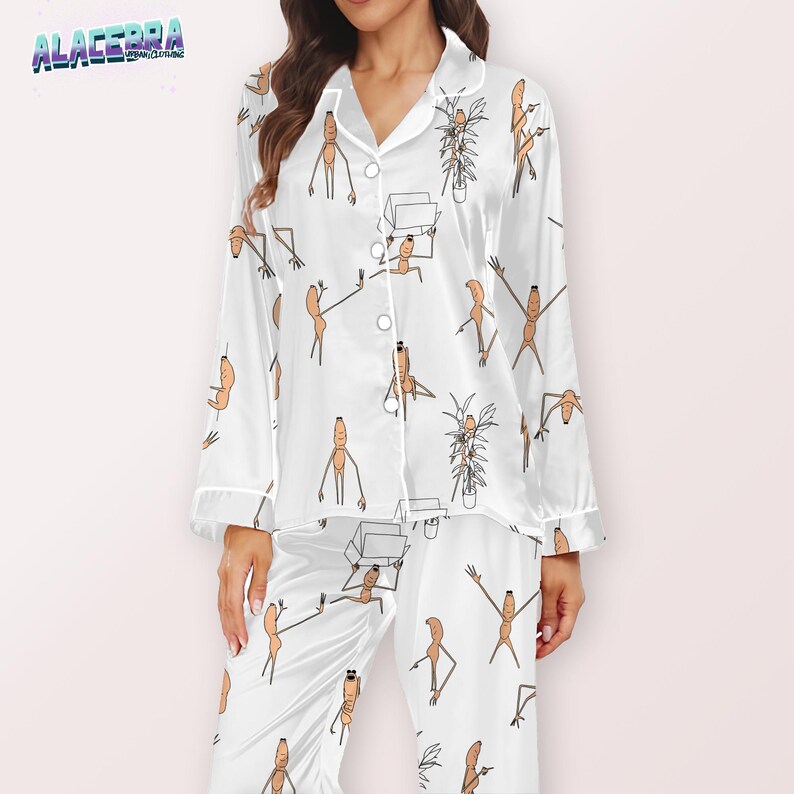 Puede incluir: Conjunto de pijama blanco con un estampado repetido de personajes de dibujos animados. La parte superior de manga larga tiene una botonadura y un cuello con solapas. Los pantalones son largos y rectos. El conjunto de pijama es de sat&eacute;n.