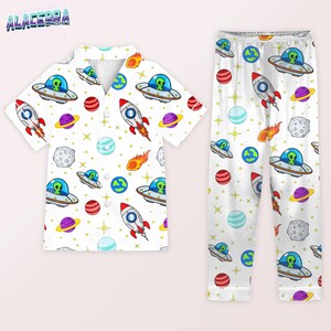Puede incluir: Conjunto de pijama blanco con un estampado repetido de extraterrestres de dibujos animados en ovnis, cohetes, planetas y estrellas. La parte superior de manga corta tiene una botonadura. El pantal&oacute;n de pijama tiene cintura el&aacute;stica.
