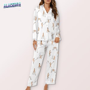 Puede incluir: Conjunto de pijama blanco con un patr&oacute;n repetido de figuras de dibujos animados en marr&oacute;n. La parte superior de manga larga tiene una botonadura y cuello con solapas. Los pantalones tienen cintura con cord&oacute;n y corte holgado. La marca "ALACERRA" es visible.