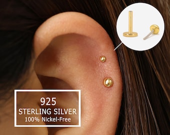 May include: Close-up of a person's ear with three gold stud earrings. The earrings are made of 925 sterling silver and are 100% nickel-free.