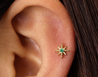 May include: A gold star-shaped earring with a green gemstone in the center.