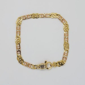 May include: A gold and rose gold two-tone chain bracelet with a lobster clasp. The bracelet is made of a mariner link chain style.