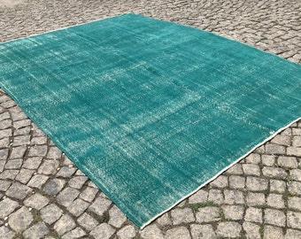 May include: A teal blue rug with a white border. The rug is made of a soft, woven material and has a distressed look.
