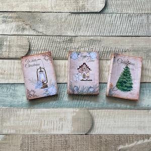 Könnte beinhalten: Drei dekorative Karten zum Thema Weihnachten mit Vintage-Designs. Die Karten zeigen eine Laterne, ein Lebkuchenhaus und einen Weihnachtsbaum. Jede Karte hat einen verwitterten, gealterten Look mit floralen und botanischen Akzenten. Der Text auf den Karten lautet "White Christmas", "Christmas Time" und "Christmas".