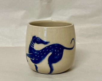 May include: A white ceramic mug with a blue silhouette of a dog on the side.
