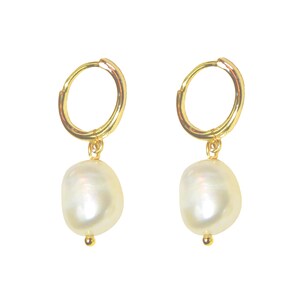 May include: A pair of gold-colored hoop earrings with a large, off-white, teardrop-shaped pearl pendant. The earrings have a simple, elegant design, with a small gold bead at the bottom of each pearl.