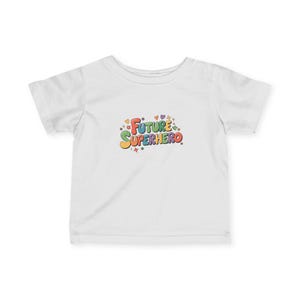 Op de afbeelding: Een wit t-shirt met de tekst "FUTURE SUPERHERO" in kleurrijke letters. Het ontwerp bevat sterren, harten en andere decoratieve elementen. Het shirt is gemaakt van een zacht materiaal en is geschikt voor kinderen.