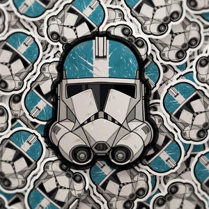 May include: A collection of stickers featuring a detailed illustration of a white and teal helmet, reminiscent of a clone trooper. The helmet has a black visor and is surrounded by other similar stickers.