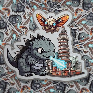 May include: A die-cut sticker featuring a cartoon gray monster with spikes breathing a blue energy beam at a tall city building, with a small winged creature flying above. The design is set against a repeating background pattern of the same image.