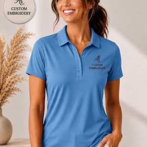 A woman wearing a blue polo shirt with the text "CUSTOM EMBROIDERY" on it, smiling and posing for the camera.