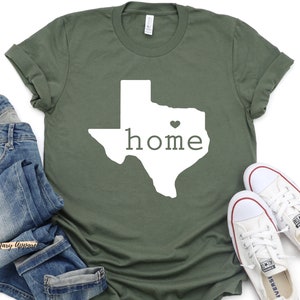 May include: A green t-shirt with a white outline of the state of Texas and the word "home" inside. A small heart is in the center of the state.