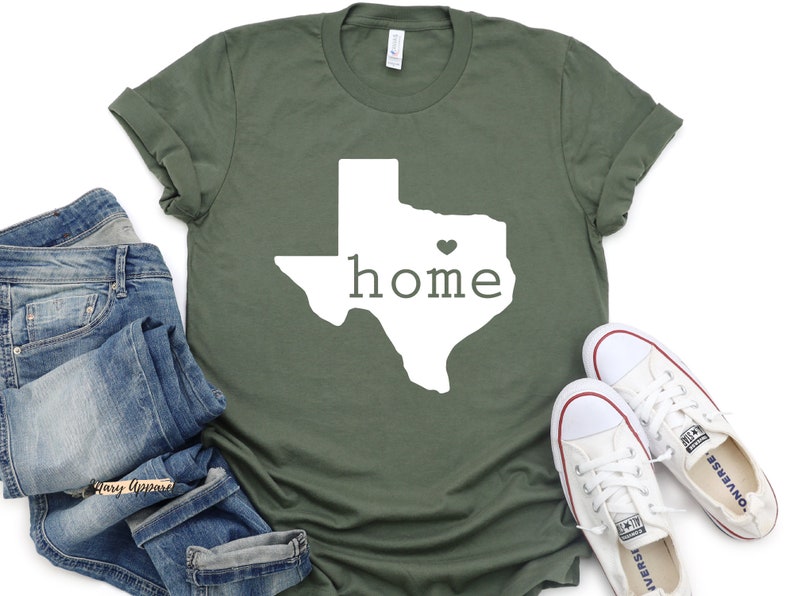 May include: A green t-shirt with a white outline of the state of Texas and the word "home" inside. A small heart is in the center of the state.