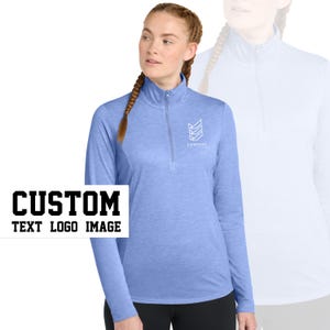 May include: A light blue long-sleeved shirt with a mock neck and a zipper. The shirt has a white logo on the front that says "COMPANY" with a geometric design. The text "CUSTOM TEXT LOGO IMAGE" is in black letters on a white background.