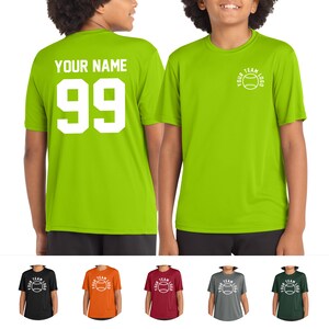 May include: Lime green athletic t-shirt with white text "YOUR NAME" and the number "99" on the back. The front features a white baseball logo with the text "YOUR TEAM LOGO". Additional shirts in black, orange, burgundy, gray, and green.