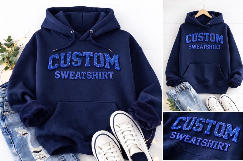 a navy blue hoodie with the text "CUSTOM SWEATSHIRT" printed on it, along with a pair of white sneakers and a pair of blue jeans.