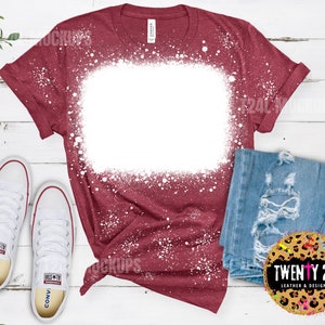 May include: A maroon t-shirt with a white bleach splattered design. The shirt has a blank white area in the center for customization.