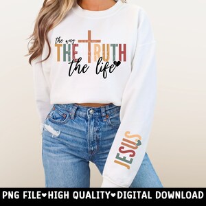 May include: A white sweatshirt with the text "the way THE TRUTH the life" in colorful block letters with a cross and a heart. The left sleeve has the word "JESUS" in colorful block letters with a heart.