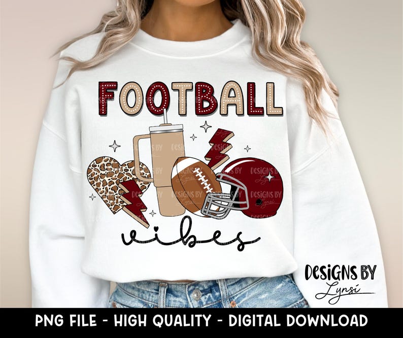 May include: White sweatshirt with the text "FOOTBALL vibes" in maroon and white. The design includes a football, a coffee cup, a leopard print heart, and a lightning bolt.
